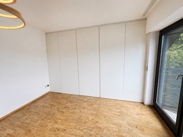 Begehbarer Einbauschrank unter der Dachschräge – geschlossene Front Raumhohe weiße Schrankfront eines begehbaren Einbauschranks unter einer Dachschräge