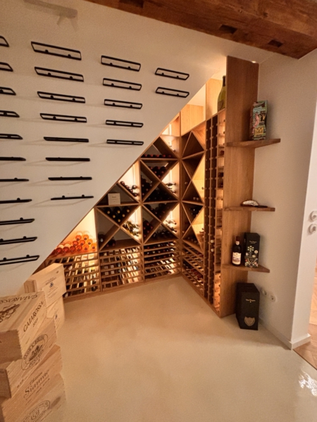 Maßgefertigtes Eiche-Weinregal mit Beleuchtung Großes beleuchtetes Weinregal aus Eiche mit diagonalen Flaschenfächern, Auszügen und Präsentationsflächen
