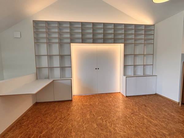 Einbauregal mit LED-beleuchteter Schiebetür Weißes Einbauregal mit Schreibtisch und geschlossener Schiebetür mit umlaufender warmer LED-Beleuchtung