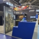 Individueller Messestand mit lackierter blauer Empfangstheke, beleuchteter Vitrine und Präsentationsflächen