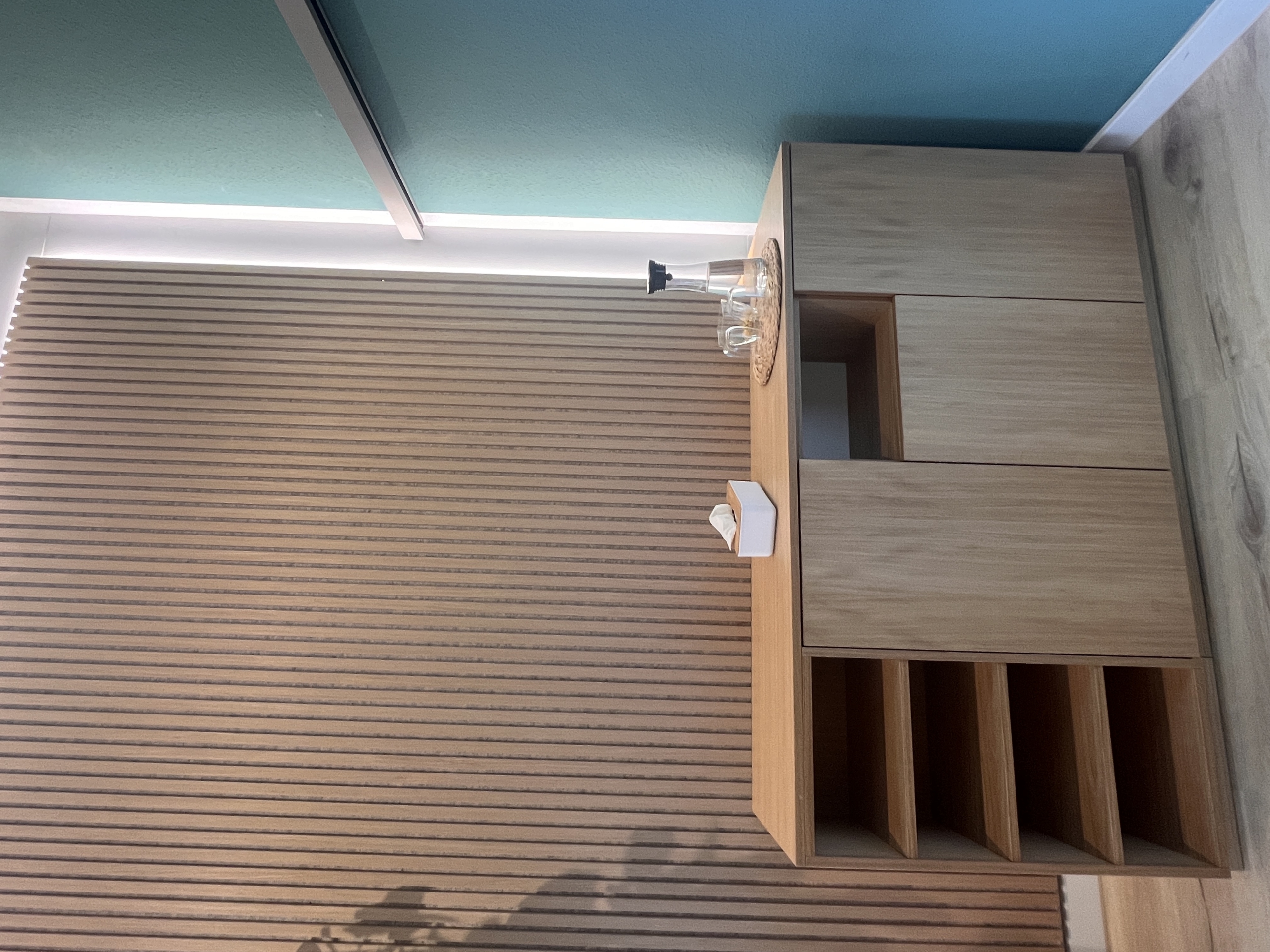 Sideboard aus Eiche vor beleuchteter Akustiklamellenwand in Köln